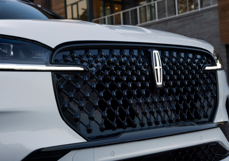 The black grille of a white 2025 Lincoln Aviator® SUV is shown with its fog lights on. | Lincoln Demo 4 in Derwood MD