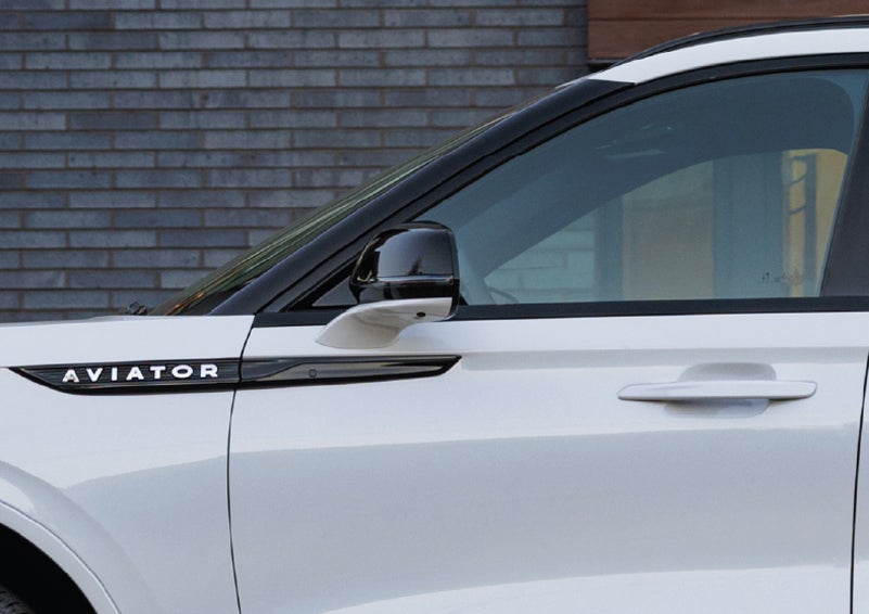 The driver’s side door and fender badging of a white 2026 Lincoln Aviator® SUV are showcased. | Lincoln Demo 4 in Derwood MD