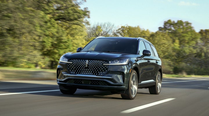 A 2026 Lincoln Black Label™ Aviator® SUV is being driven down a road lined with trees. | Lincoln Demo 4 in Derwood MD
